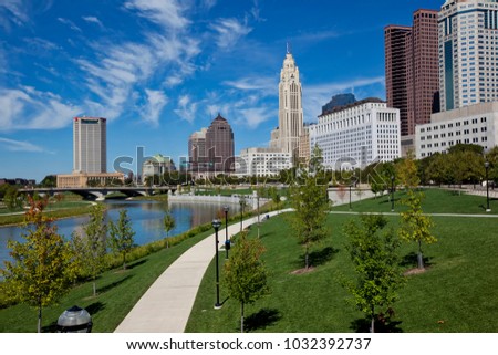 The skyline of downtown Columbus, Ohio along the Scioto River is crisp and clear.  Wispy clouds in the sky add drama to the cityscape.
