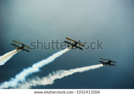 Group of vintage single engine propeller biplanes aircrafts flying with dark stormy sky background