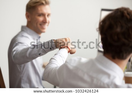 Smiling male colleagues fist bumping at workplace, happy friends greeting, partners sharing success, employees celebrating good teamwork result, workers supporting motivation concept, close up view Royalty-Free Stock Photo #1032426124