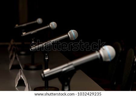 Microphones in press conference room, prepared for press conference. Royalty-Free Stock Photo #1032429235