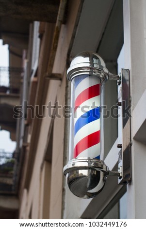 closeup of barber shop pole sign with blue and red moving stripes on a building facade