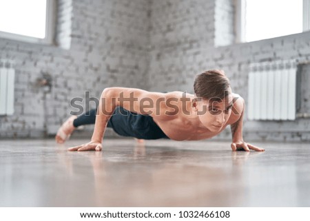 Athletic young man doing push ups on the floor. Young man workout in fitness club.