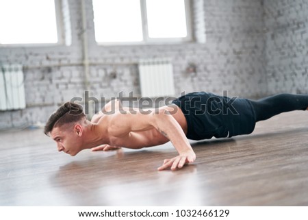 Athletic young man doing push ups on the floor. Young man workout in fitness club.