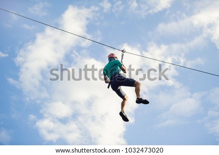 a man descends on a rope, a sport in an extreme park, A man walking along a zip line, Royalty-Free Stock Photo #1032473020