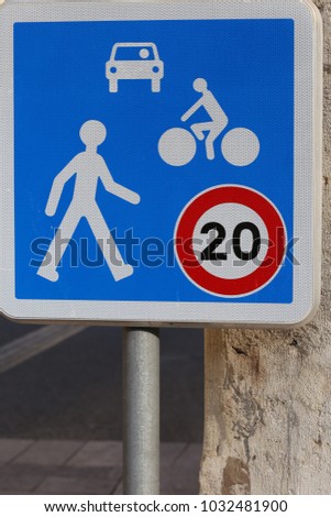 Close up view of a french traffic sign in a pedestrian street. Symbol indicating that the speed is limited at 20 kilometers per hour for cars and cycles. Blue and white metallic sign, Urban image.  