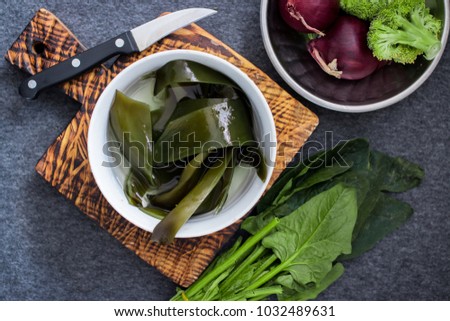 Wet soaked kombu seaweed leaves (nori, wakame, kelp) good to serve with fresh vegetables - broccoli, onion and spinach. Raw diet. Asian, japanese traditional food. Vegan, vegetarian healthy concept. Royalty-Free Stock Photo #1032489631