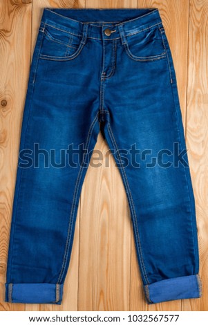 dark blue jeans for a boy on a wooden floor top view