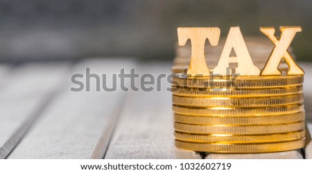 TAX word with golden coins on wooden table. Conceptual image.
