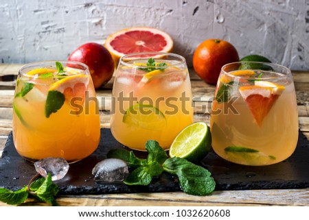 Grapefruit and lime, mint gin cocktail, refreshing drink with ice on wooden background. Selective focus