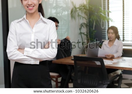 Leadership young Asian business woman standing with her colleague in office background.