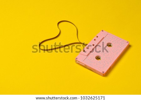 Heart shape from audio cassette tape over yellow paper background, top view. Hipster Love.
