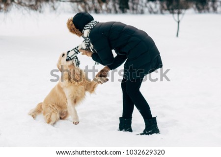 Picture of woman in black jacket with retriever walking in winter park