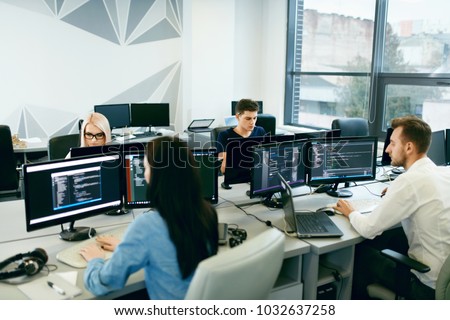 People Working In Modern Office. Group Of Young Programmers Sitting At Desks Working On Computers In It Office. Team At Work. High Quality Image