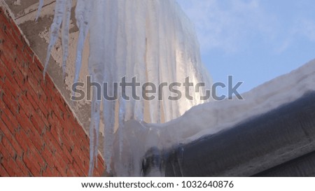 Icicles on the heating pipes and a brick wall.