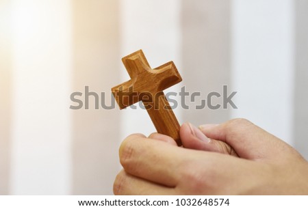 wooden cross in prayer hand isolated on white and grey background, with blank copy space, warm light tone