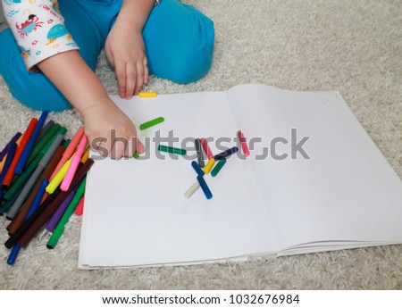 
the child draws with pencils
