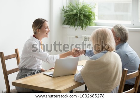 Smiling female lawyer, real estate agent or financial advisor handshaking older senior couple, insurance broker and aged family shake hands making purchase deal, investment or greeting at meeting Royalty-Free Stock Photo #1032685276