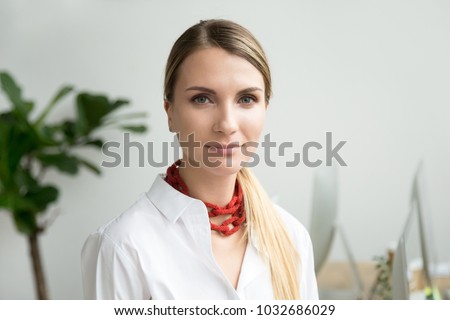 Confident beautiful young businesswoman looking at camera, ambitious serious lady entrepreneur posing in office, independent attractive woman or successful female business owner head shot portrait