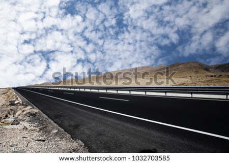 Asphalt road closeup with blue sky. Empty highway with cloudly blue sky background.