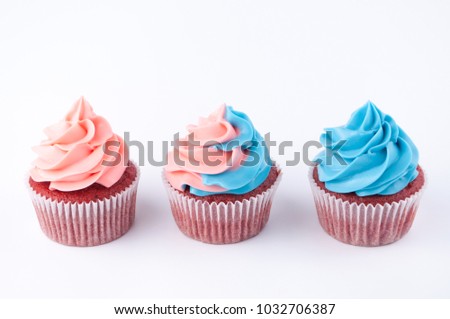 Cupcakes red velvet with blue and pink whipped cream on white background. Picture for a menu or a confectionery catalog.
