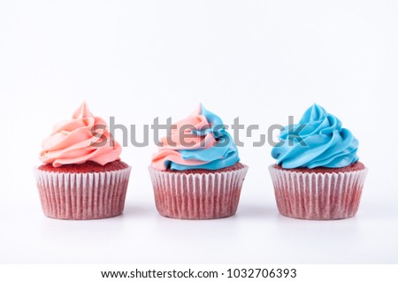 Cupcakes red velvet with blue and pink whipped cream on white background. Picture for a menu or a confectionery catalog.