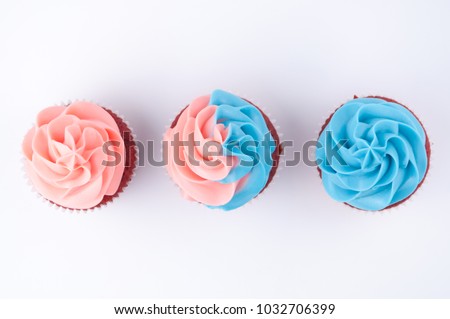 Cupcakes red velvet with blue and pink whipped cream on white background. Picture for a menu or a confectionery catalog. Top view.