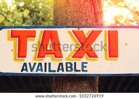 A sign informing that a Taxi is possible. Plate on a tree in the sun.