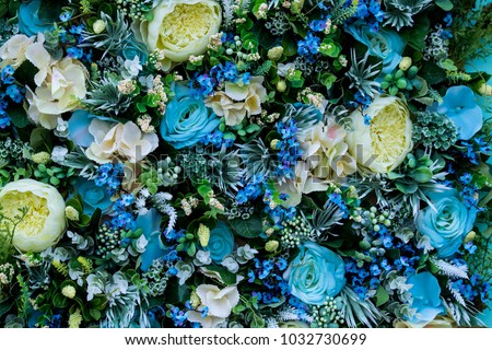 Colorful floral background of blue roses, greenish-white ranunculus, other flowers, leaves and roots. Festive design of premises. Painting from flowers on wall