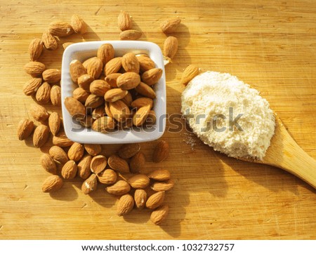 Almond flour in a wooden spoon on a background of nuts almonds. 