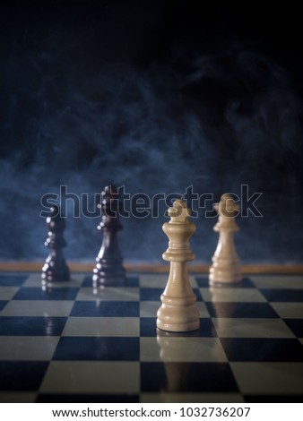 Chess board game concept of battle, war and strategy. Chess figures on a dark background with smoke and fog. Selective focus