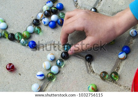 the children gathering colored glass balls and marbles pouring around,