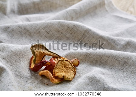 Top view close-up picture of dried apples on light cotton tablecloth, selective focus.