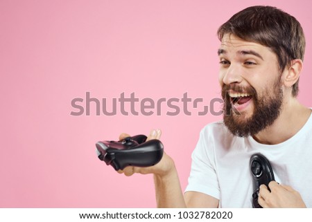  joyful man with a beard holding a joystick on a pink background                              