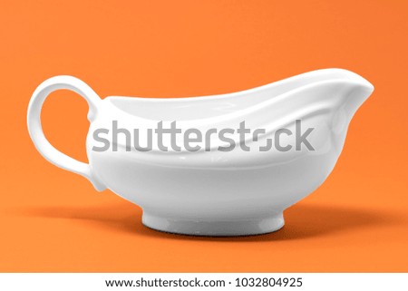A white jug set against a bright orange background