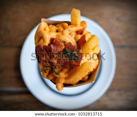 Delicious french fries topping with cheddar cheese cream and crispy bacon on close up top view Royalty-Free Stock Photo #1032813715