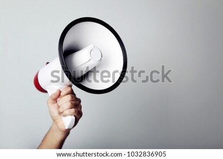 Female hand holding megaphone on grey background Royalty-Free Stock Photo #1032836905
