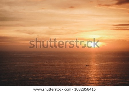 a scenic romantic landscape background picture of sunset on the horizon skyline in the ocean form the coast and the sun light reflecting with the sea water with ship sailing across the ocean 