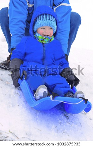 Happy toddler sledging with his father