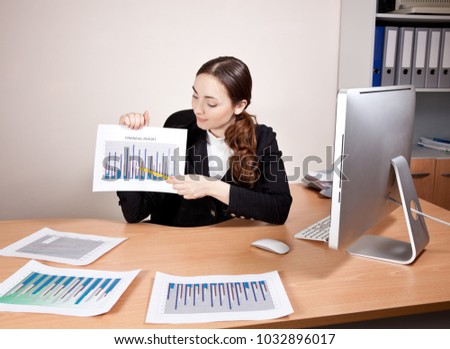 Beautiful young businesswoman with financial reports at the office