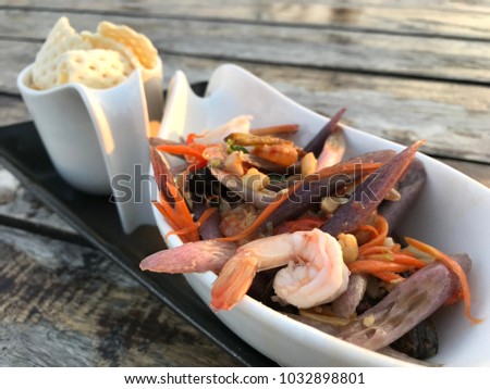 Thai Traditional And Popular Food : Thai dressed salad, Thai call 'Somtam Lai Bua' . Lotus stem spicy salad with shrimp in white ceramic bowl on wooden plank.