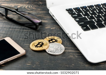 Bitcoin coins with a laptop, a mattress and glasses on the table