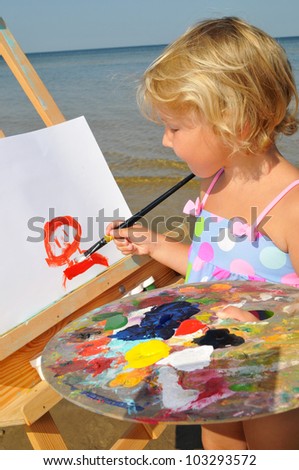 The cute baby painting brush watercolors portrait on a easel