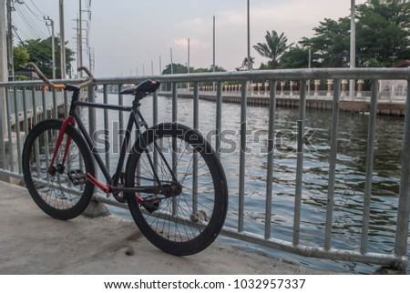 Black and red sport professional high speed fixed gear track bicycle standing near a fence and river background