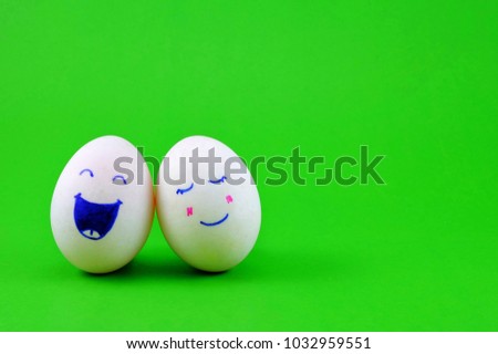 Couple of eggs with happy face on green background with copy space.