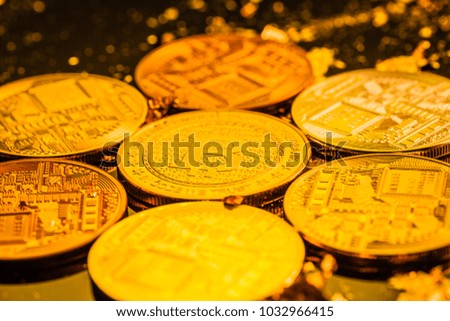 Studio shot of multiple bitcoin physical golden coins on a dark background with gold flakes. Bitcoin is a blockchain crypto currency