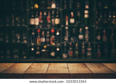 Empty the top of wooden table with blurred counter bar and bottles Background /For montage product display or design key visual layout.