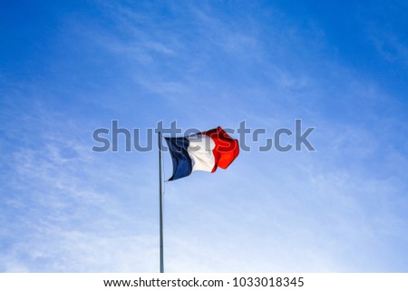 French flag waving the wind in Paris. Clear blue sky background. France.