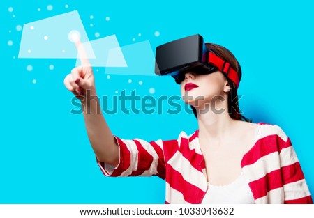 portrait of beautiful young woman with virtual reality gadget on the blue background