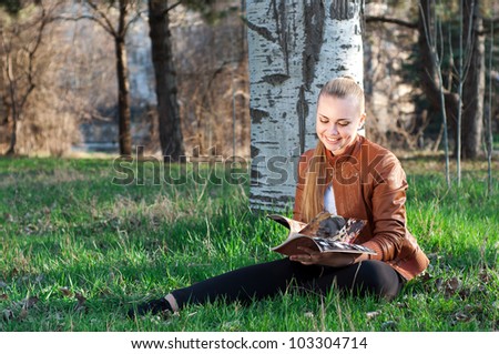 portrait of smiling young woman reading magazine in the park
