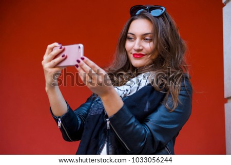 Woman taking selfie in front of red background